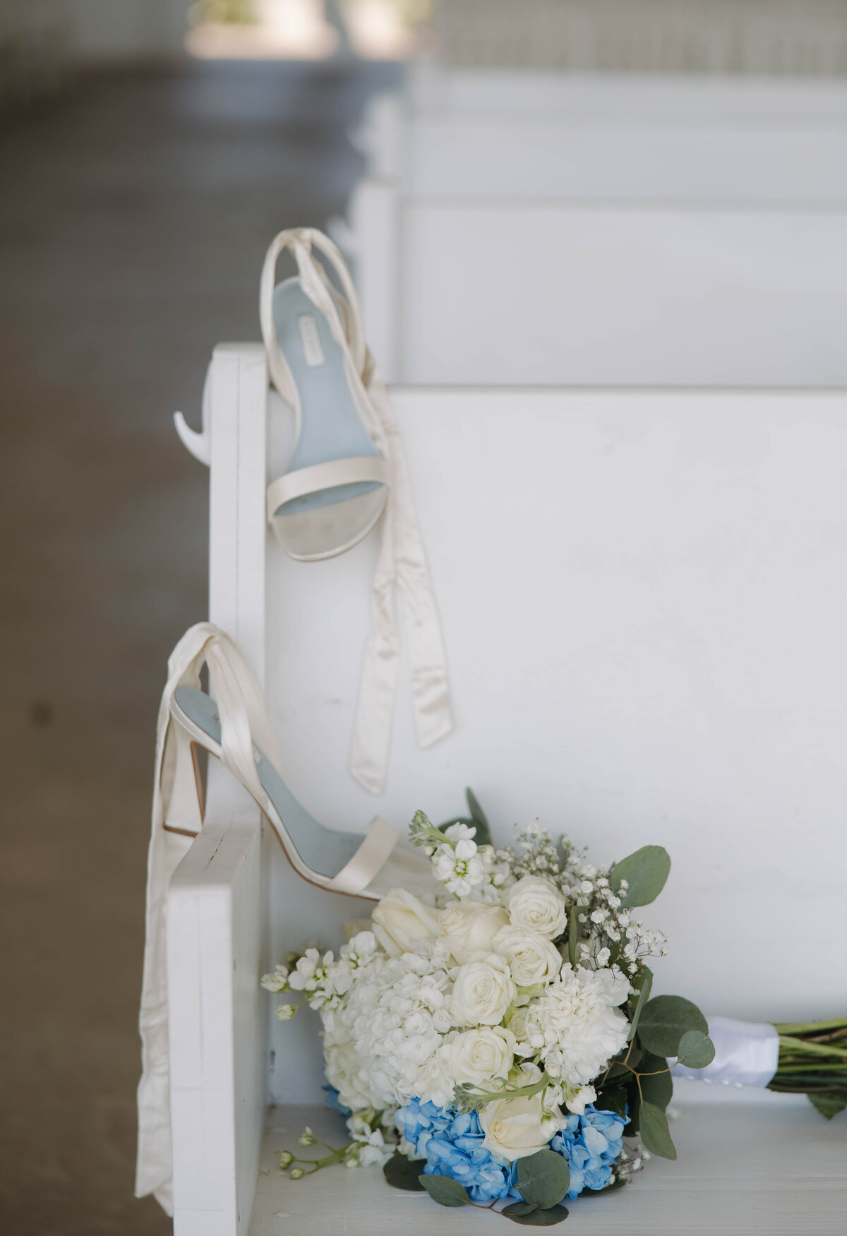 bride shoes and bouquet on pew 