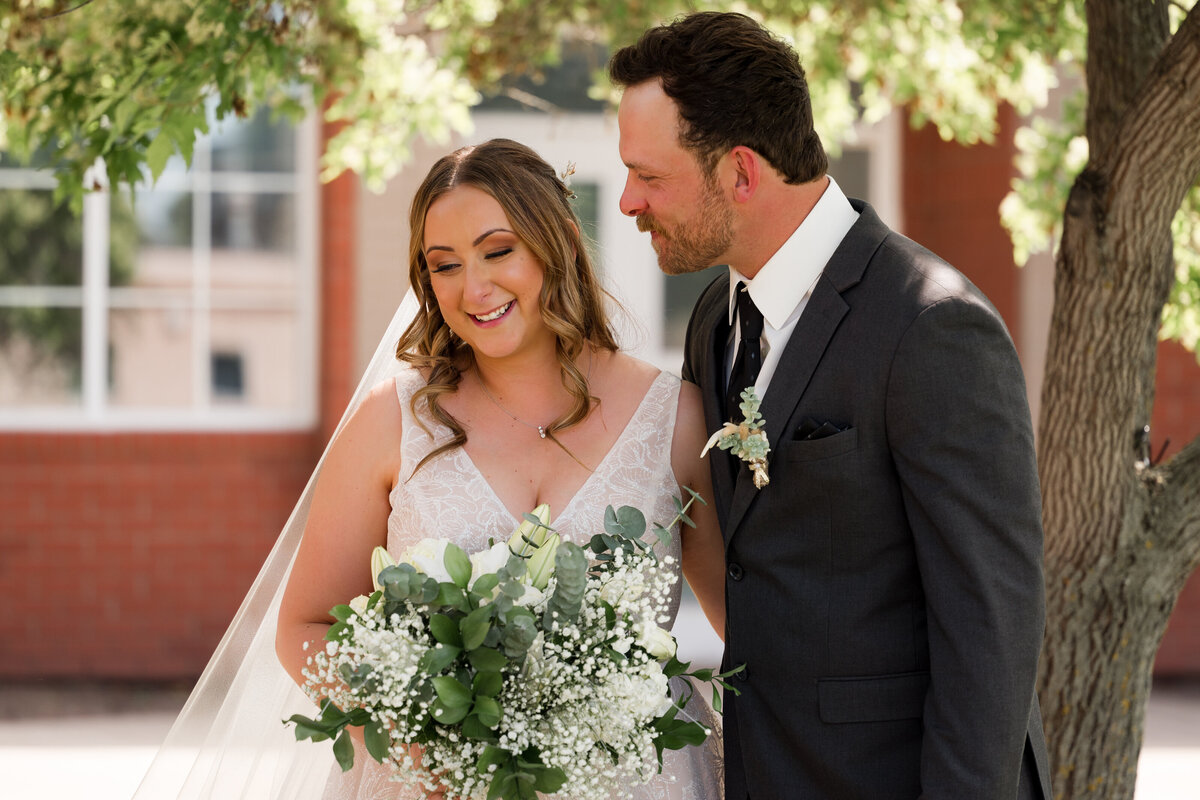 bride and groom stand under a tree  on wedding day