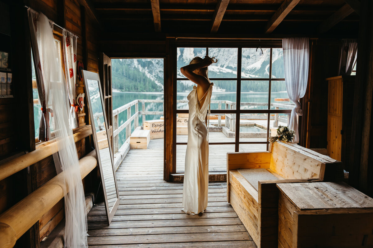 Bride standing in window light at Lago di Braies boathouse
