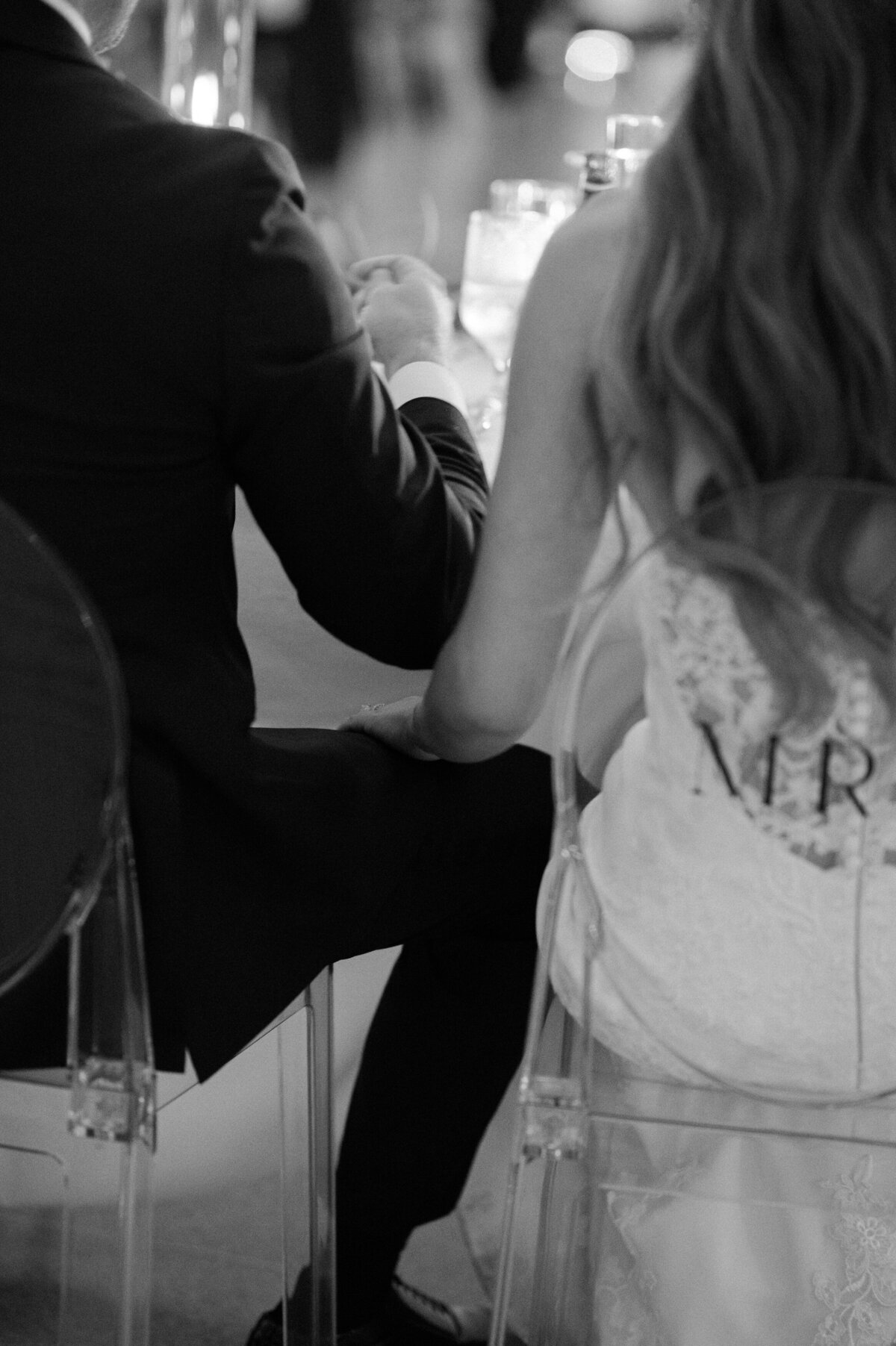 The backs of the bride and groom as they sit at their reception table