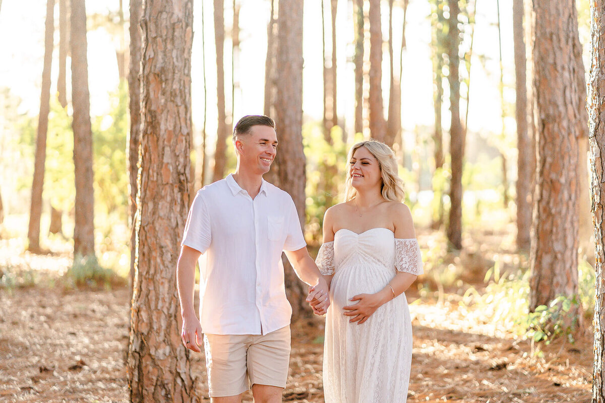 couple walking in pine forest having pregnancy photos taken with hikari lifestyle photography