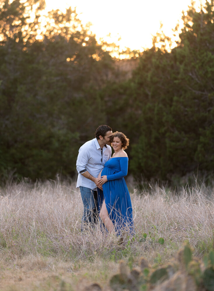 Maternity photo of smiling couple by the creek in Austin, TX during sunset