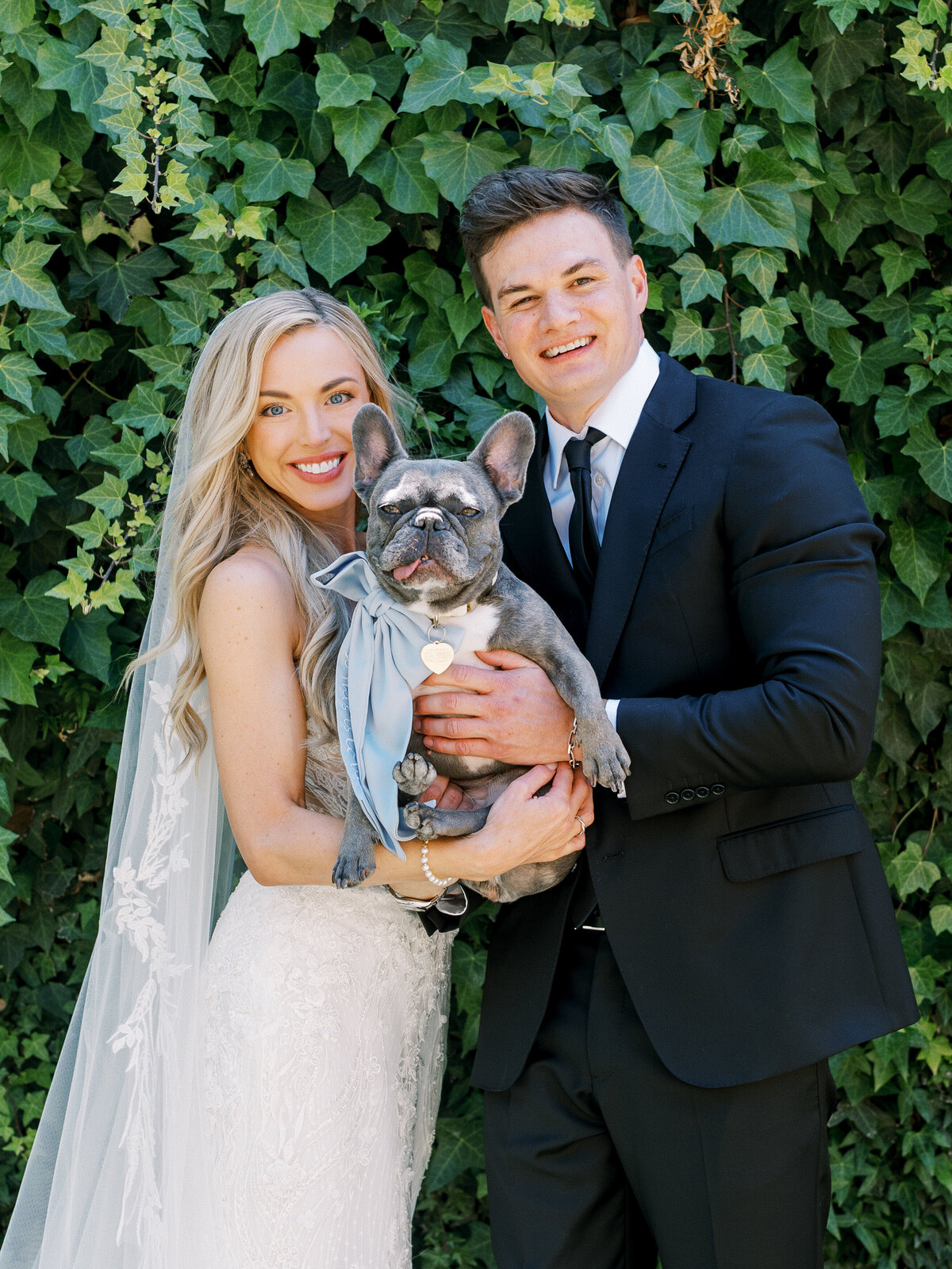 adorable couple holding their frenchie during a chateau Noland wedding photoshoot by a California wedding photographer