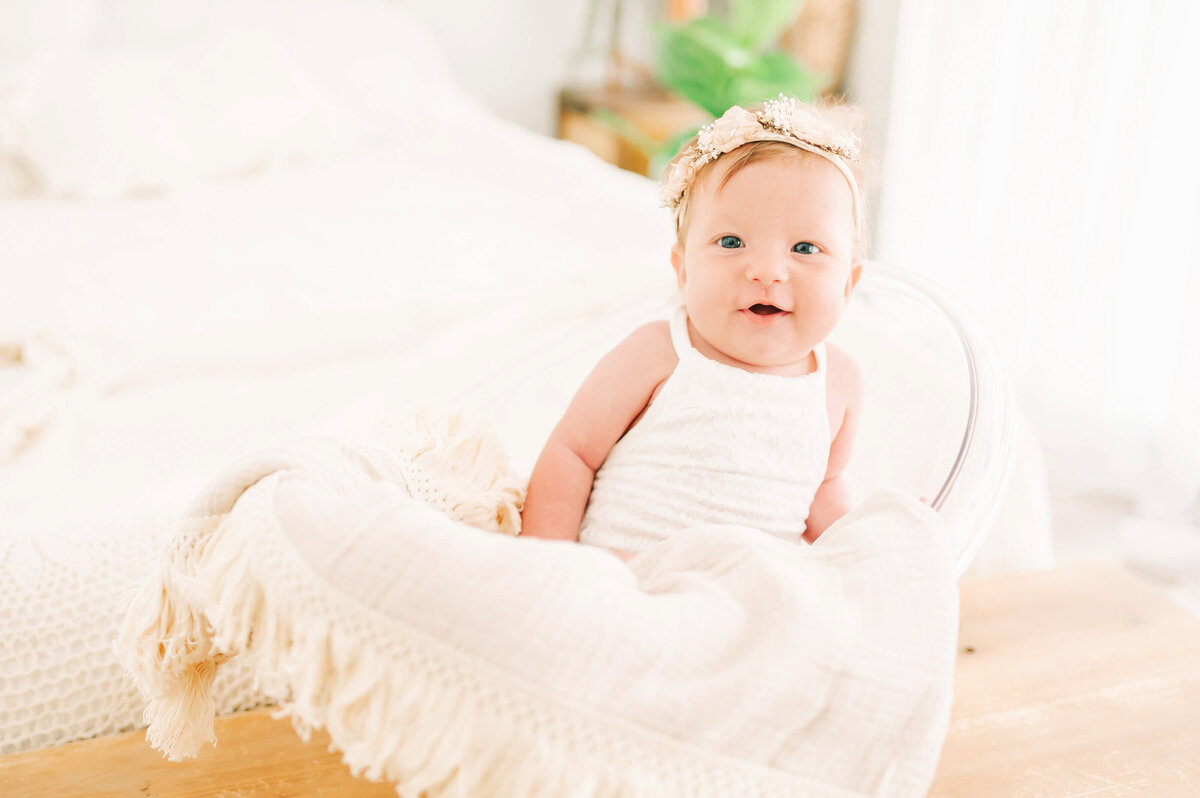smiling baby girl in a bucket captured by  Branson MO baby and childrens photographer Jessica Kennedy of The XO Photography