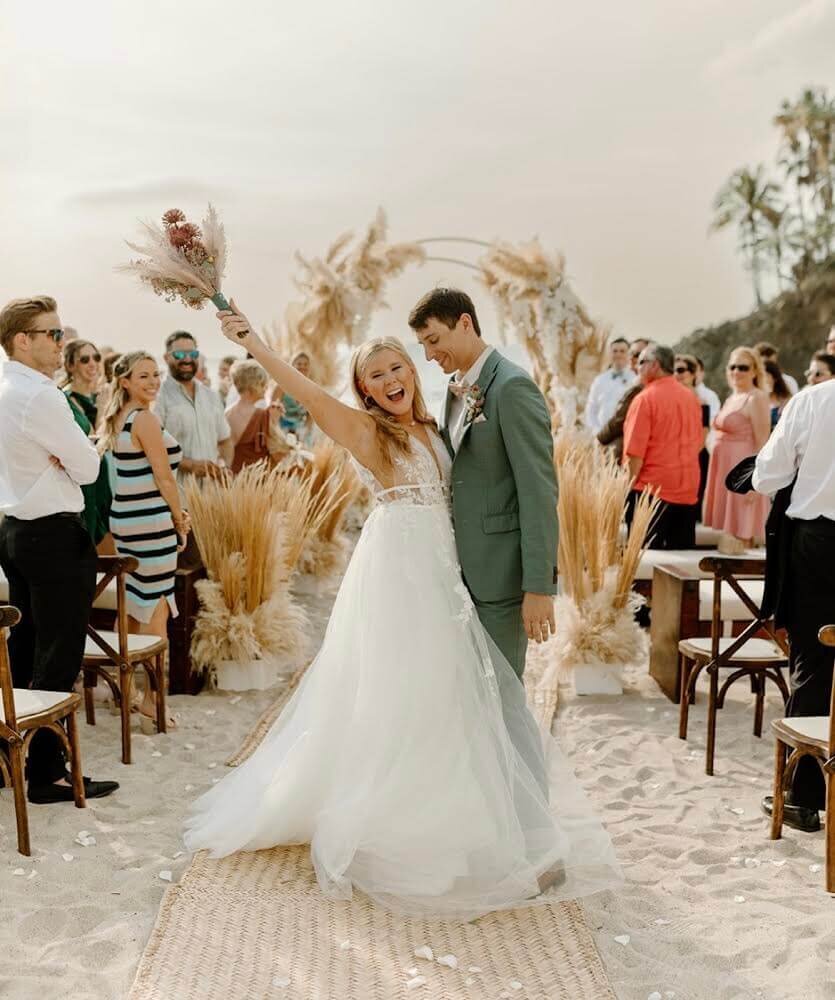 Bride and groom celebrate a joyful beach ceremony, with the bride’s radiant look created by a mobile makeup artist near me, perfect for destination weddings and on-location styling.