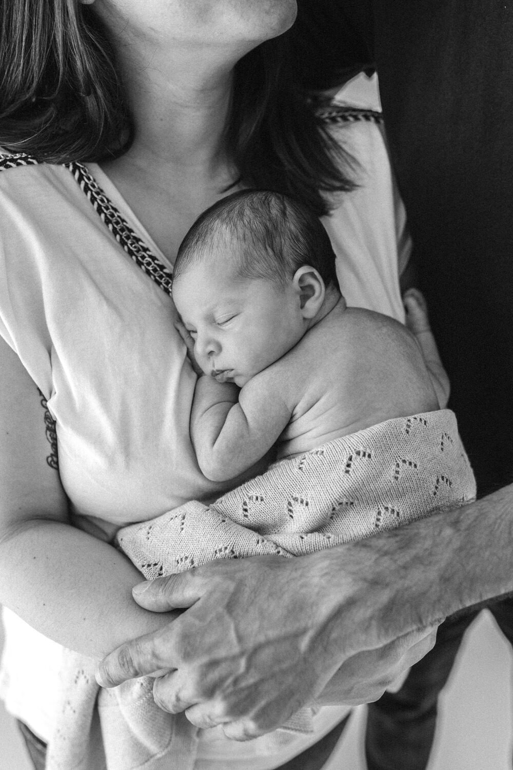 close up photograph of newborn baby being held in mum and dads hands