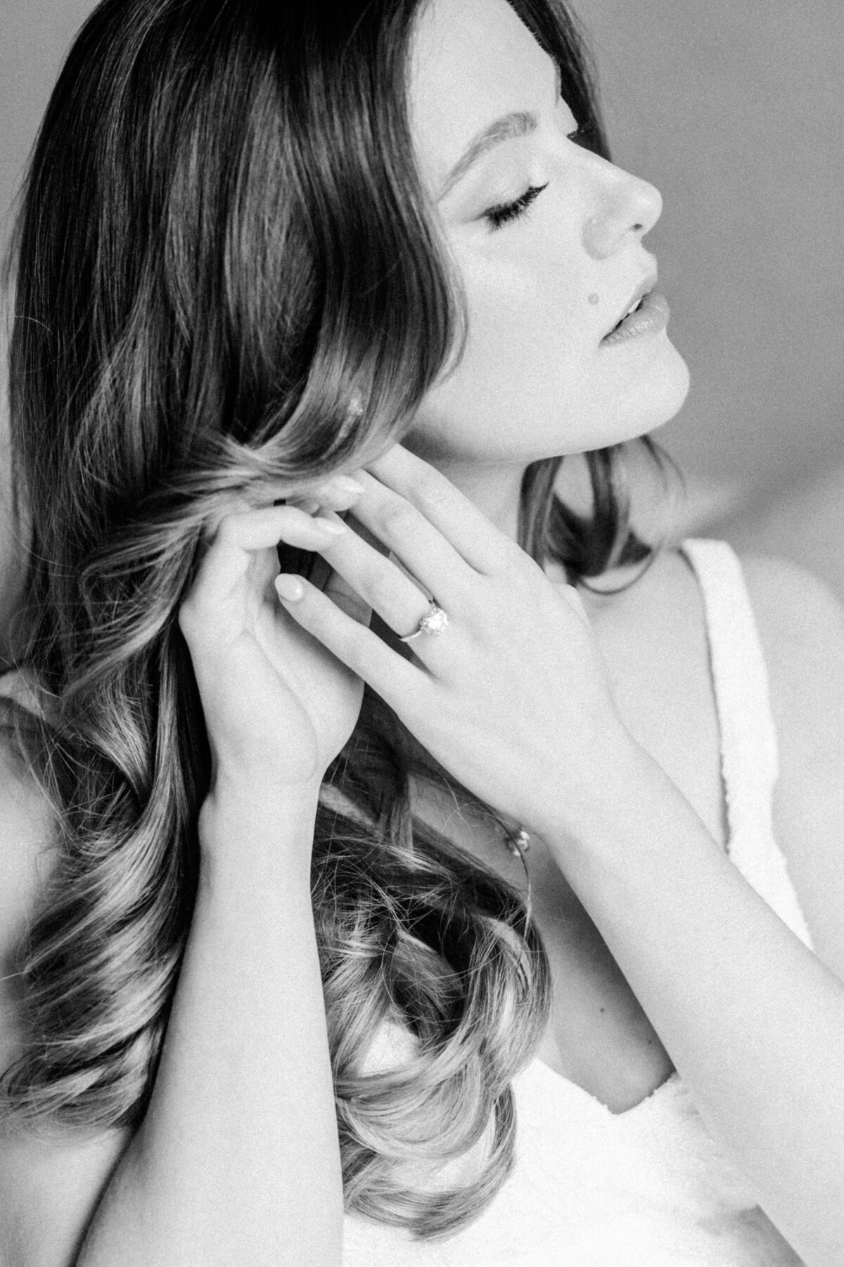 A soft, close-up portrait of a beautiful pregnant bride gracefully putting on her earrings, capturing her natural beauty and elegance.