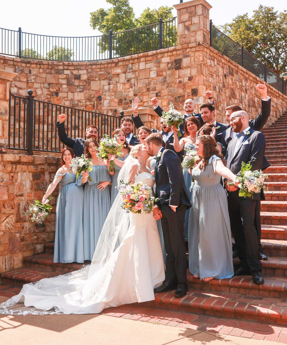 bride and groom kissing on stairs with bridal party cheering them on by Atlanta Wedding Photographer Amanda Richardson Photography