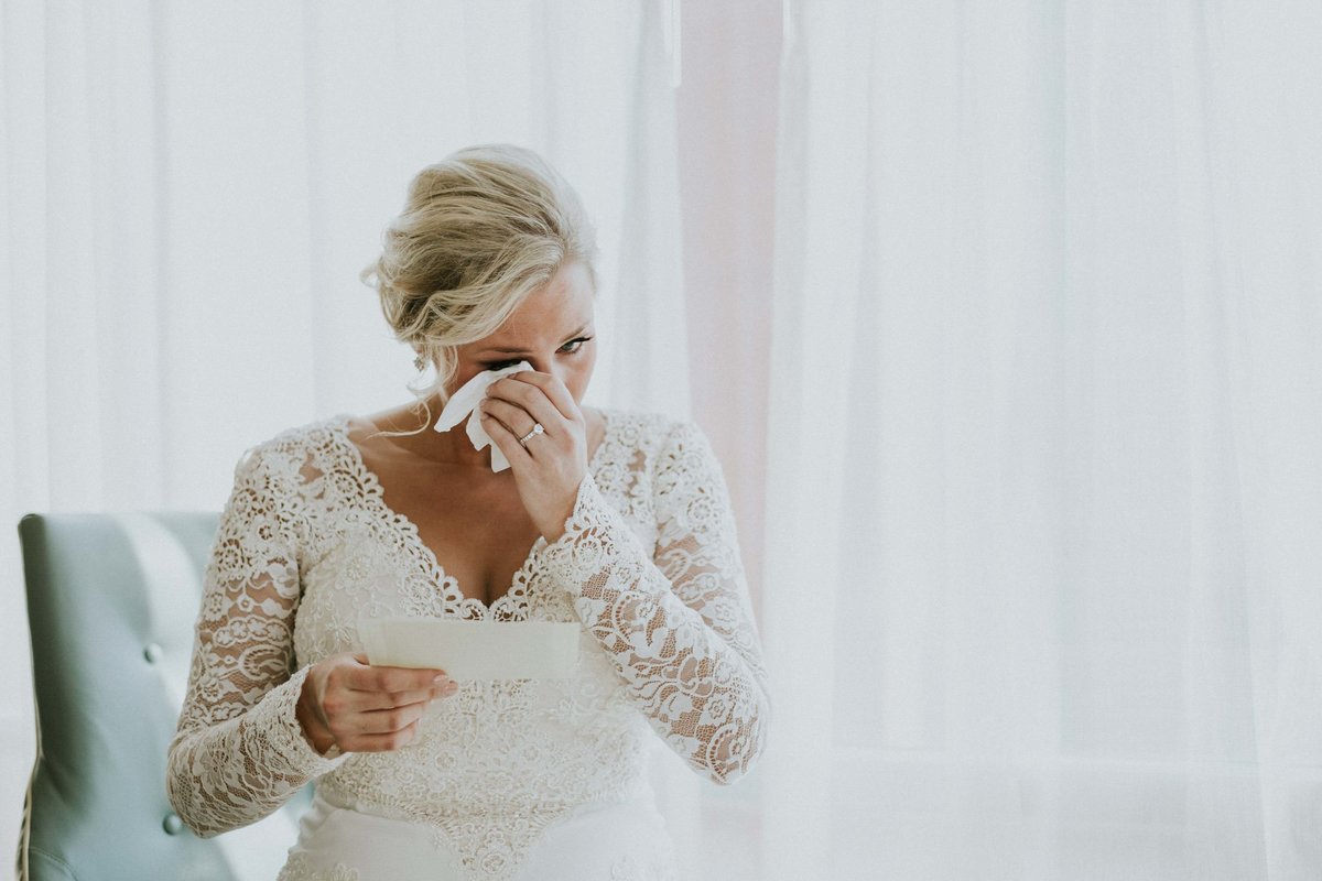 Bride holds tissue to eye while reading letter from groom at Scottish Rite wedding