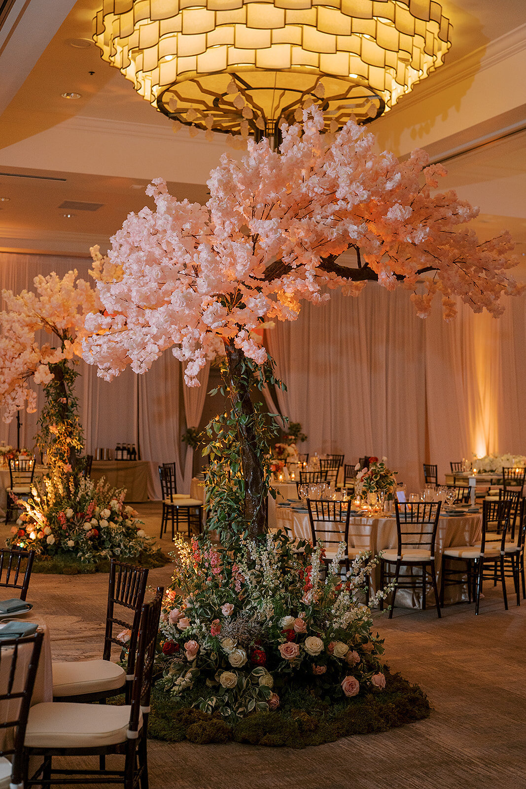 Synthetic trees with pink blooms add a fairytale ambience to the ballroom reception at the Four Seasons