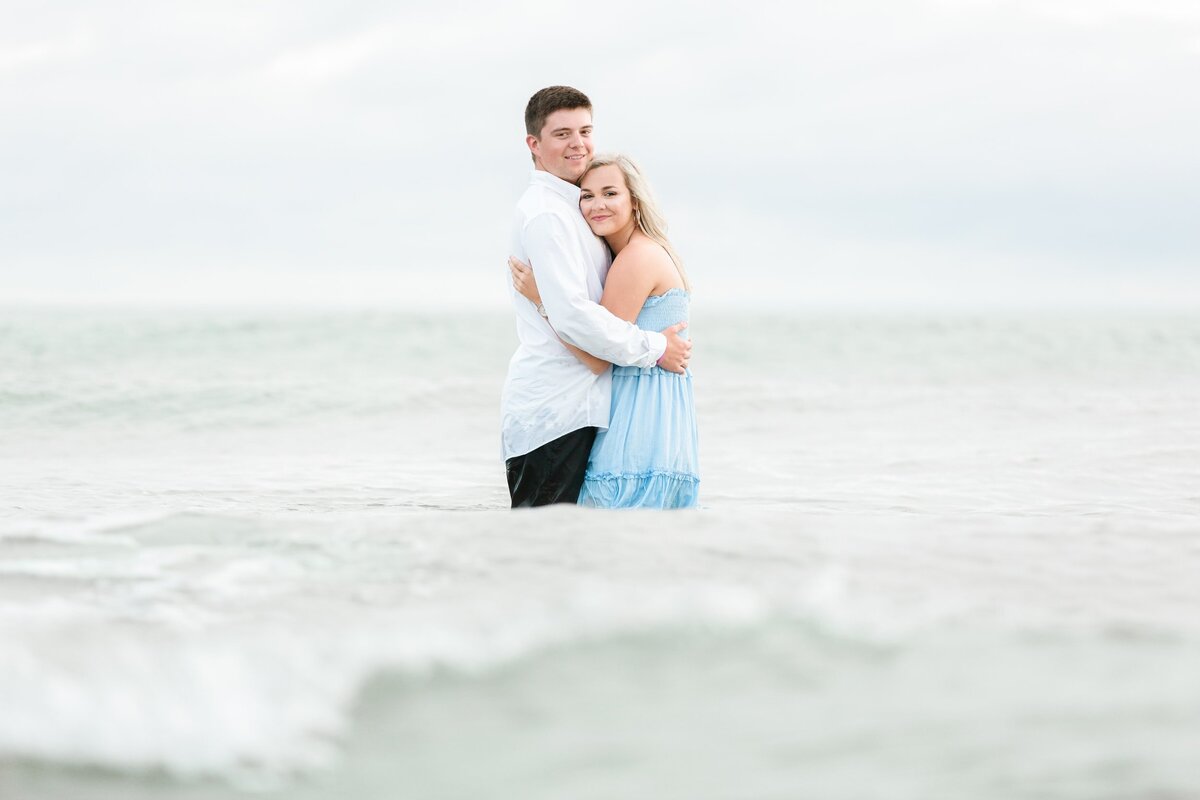 Young couple play in the water at the beach
