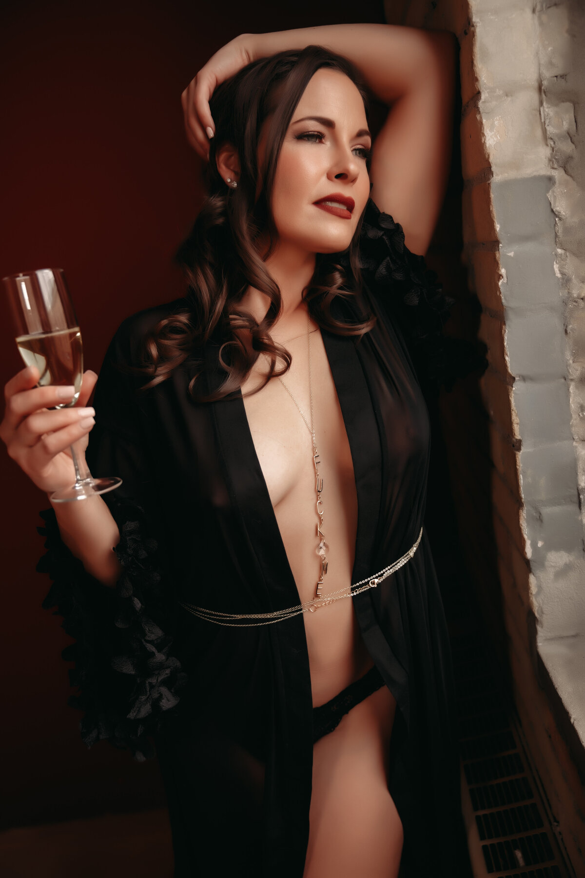 Woman posing at Minnesota boudoir studio wearing black robe and holding a champagne glass