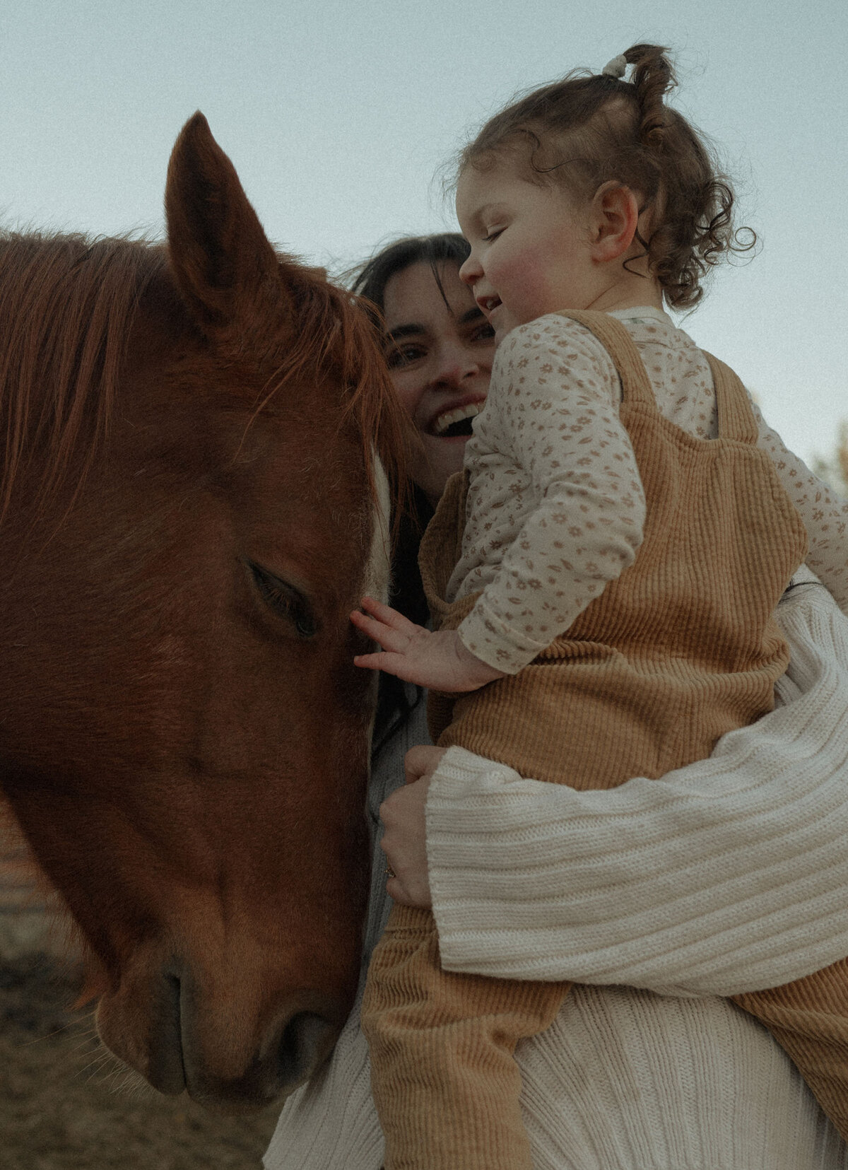 mother holds daughter while they pet and say hello to a horse on a ranch in central Oregon