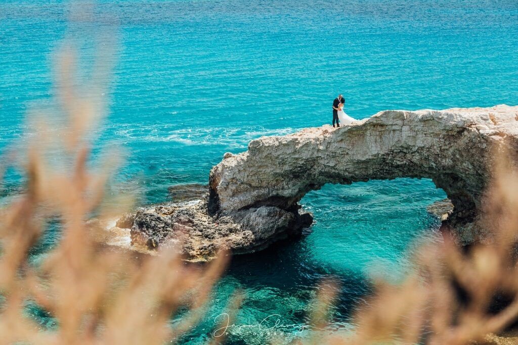 Bride & Groom kissing on a bridge above the water taken from afar