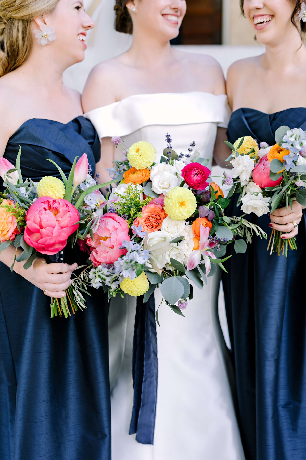 Navy satin bridesmaids dresses with colorful bouquets