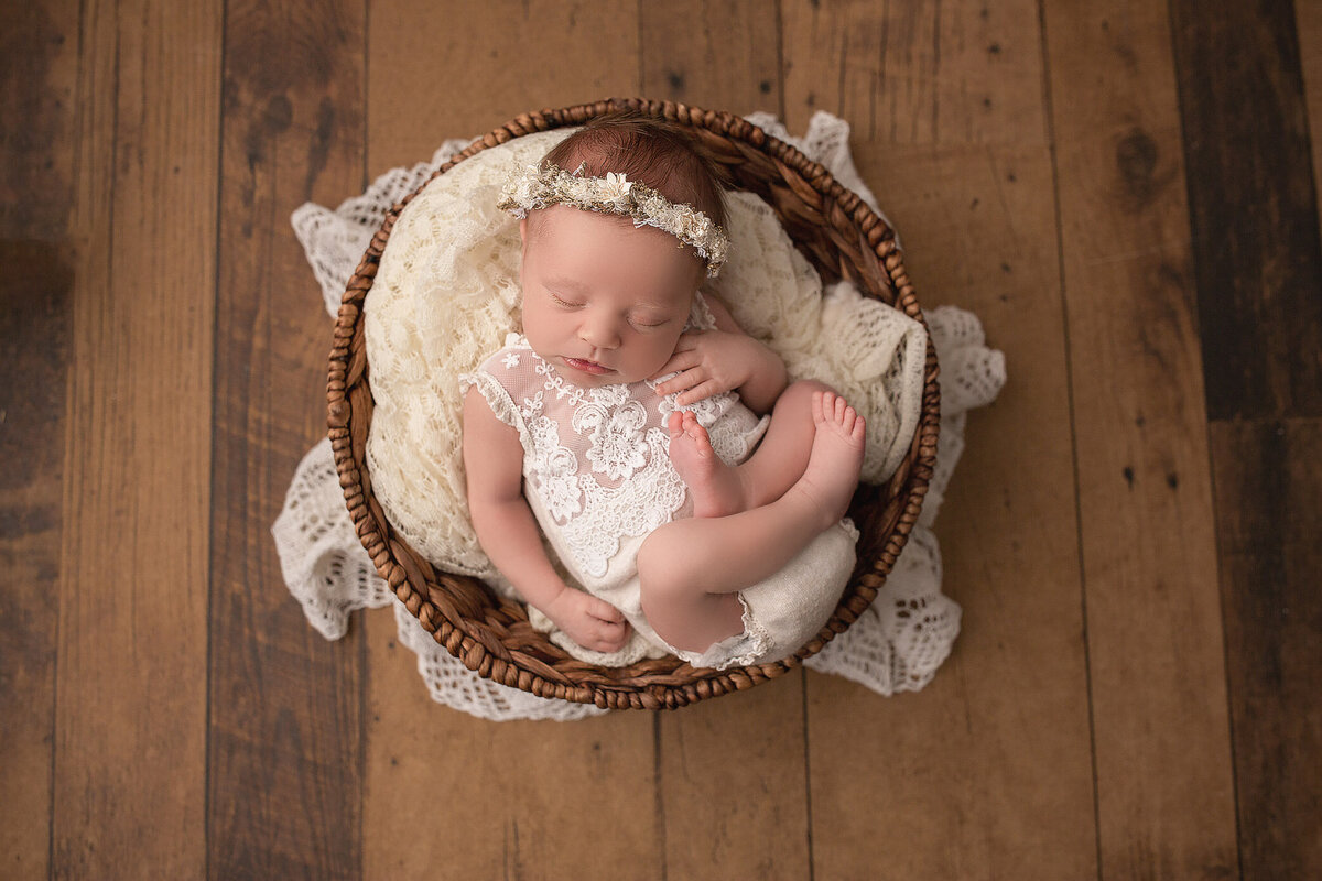 adorable baby curled up in a basket for her photoshoot in Haldimand County