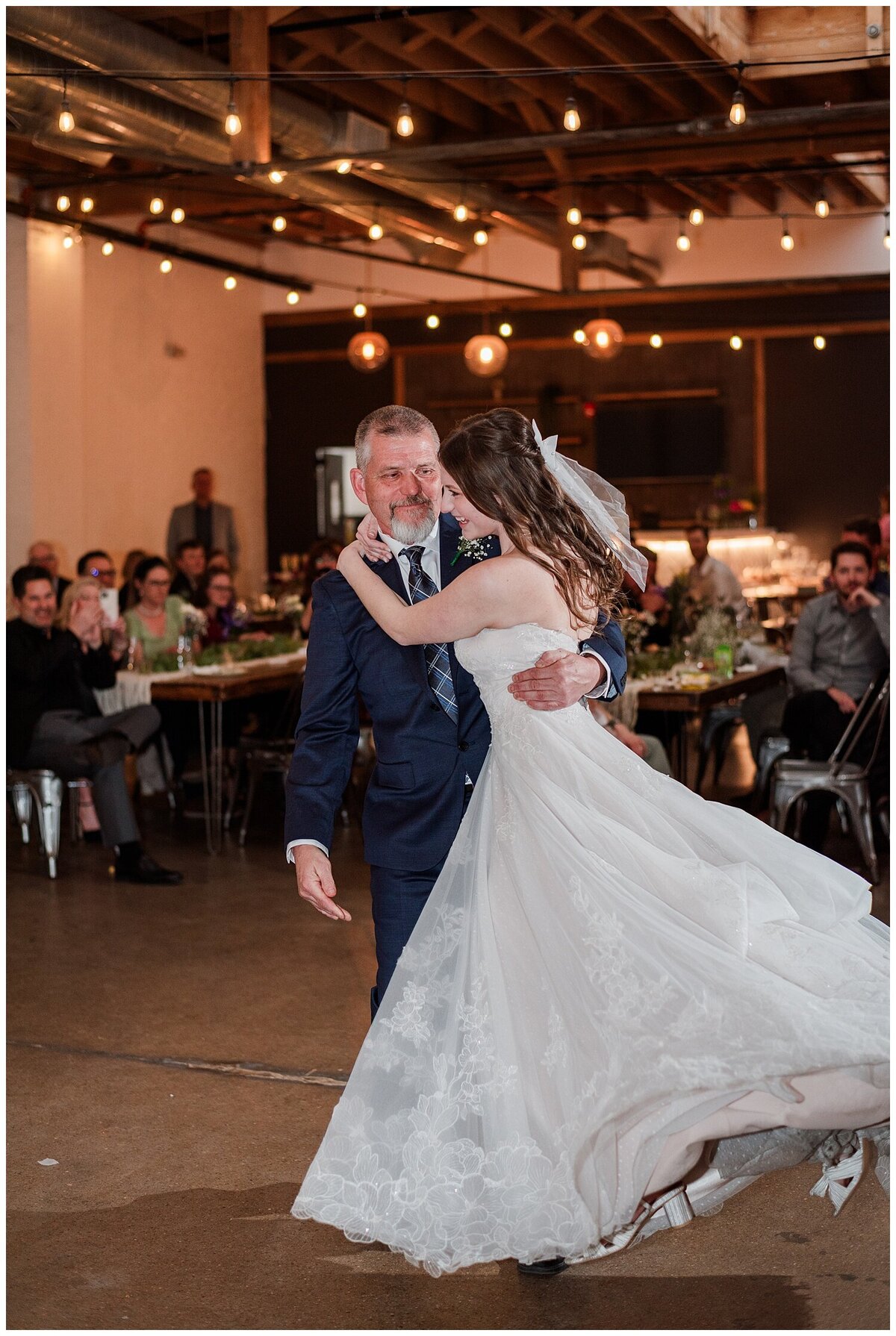 A dad picks up her daughter during their father-daughter dance at her wedding and spins her around as she smiles