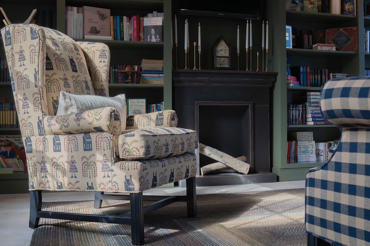 library reading wingback chair with pillow  in front of built-in library shelves filled with books