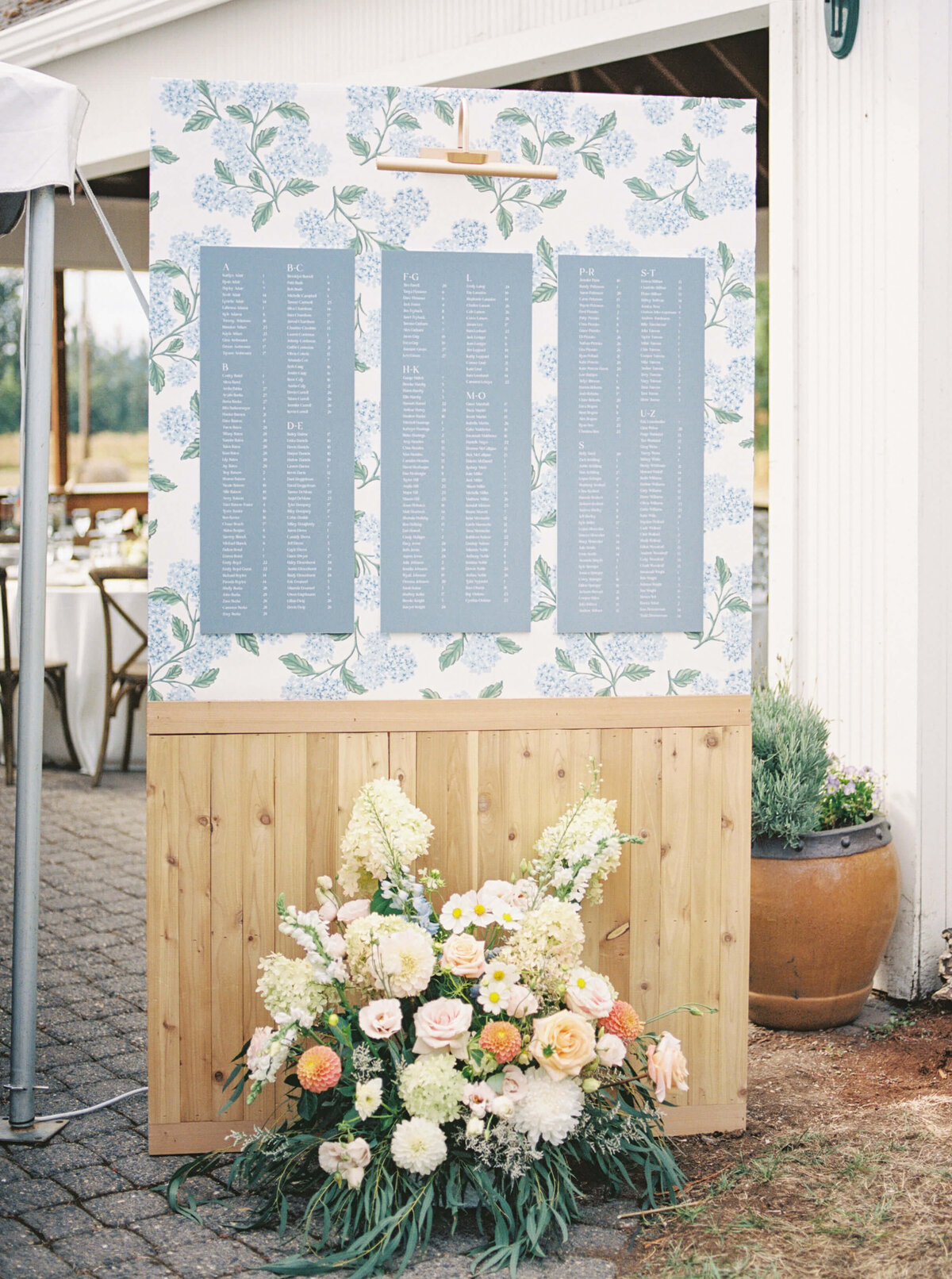 A decorative seating chart with a flower arrangement placed in front of it at a luxury wedding in Oregon.