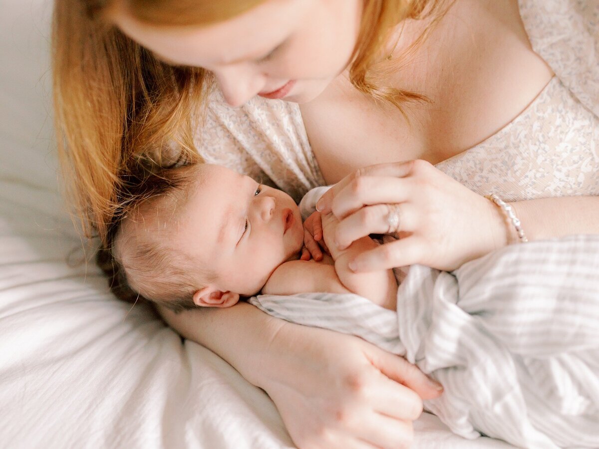 newborn-in-moms-arms-laying-in-bed