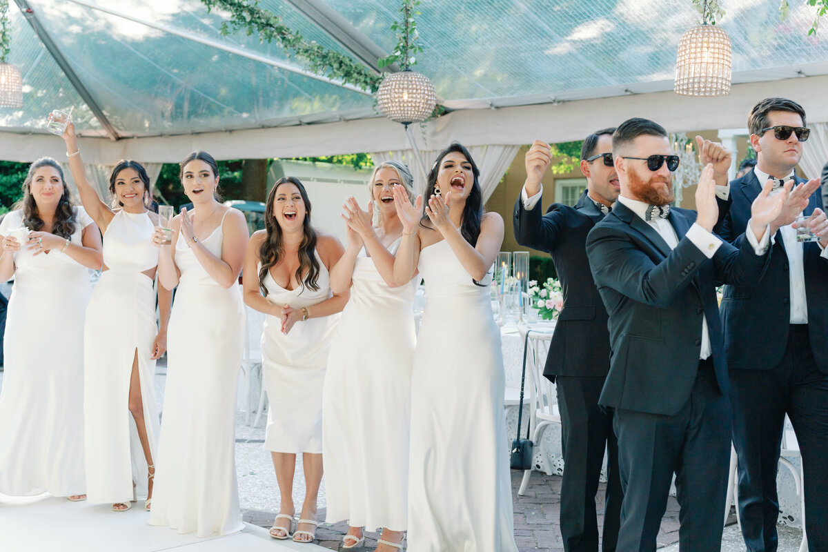 Bridal party celebrates bride and groom grand entrance at outdoor spring wedding reception in downtown Charleston. Kailee DiMeglio Photography.