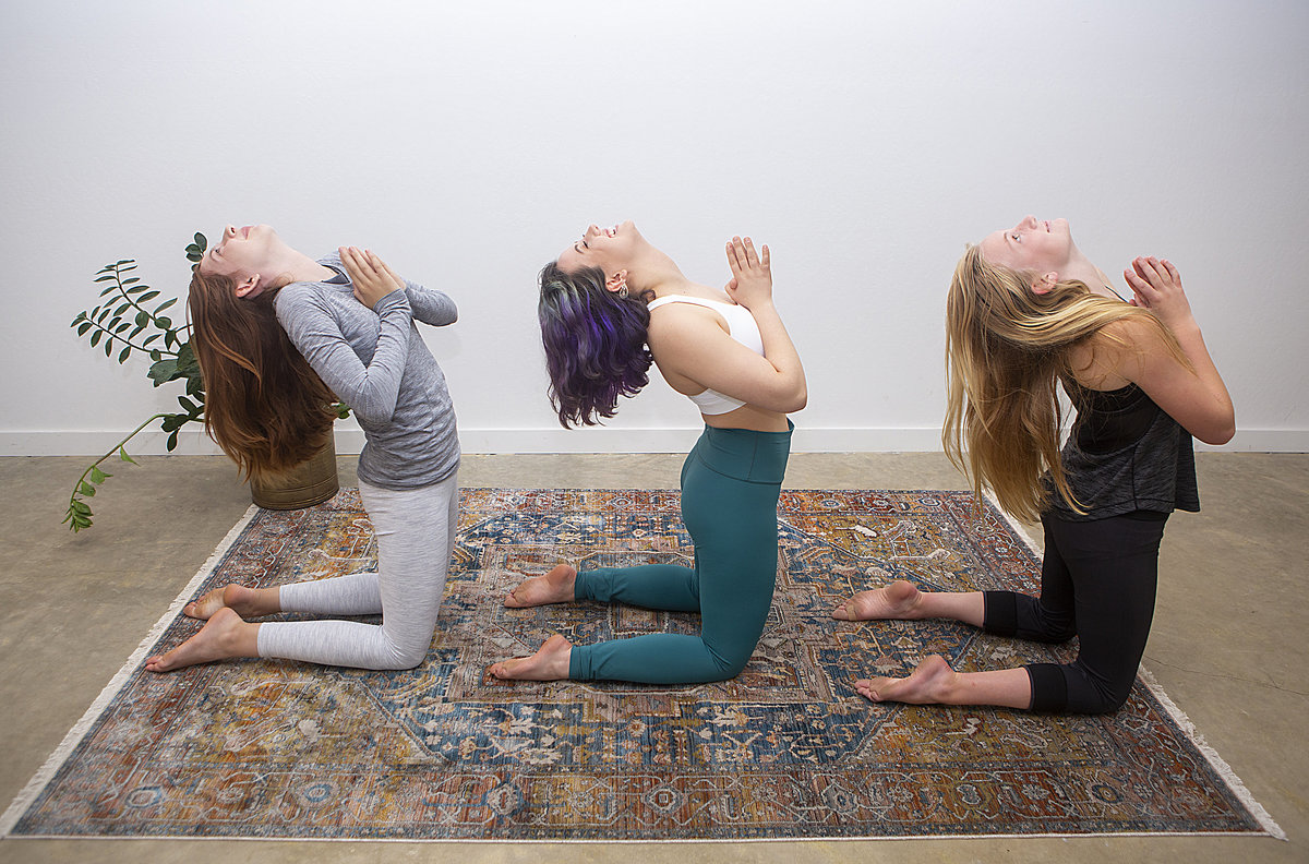 3 female yoga students hold camel pose smiling at Hotsource Yoga in Aptos