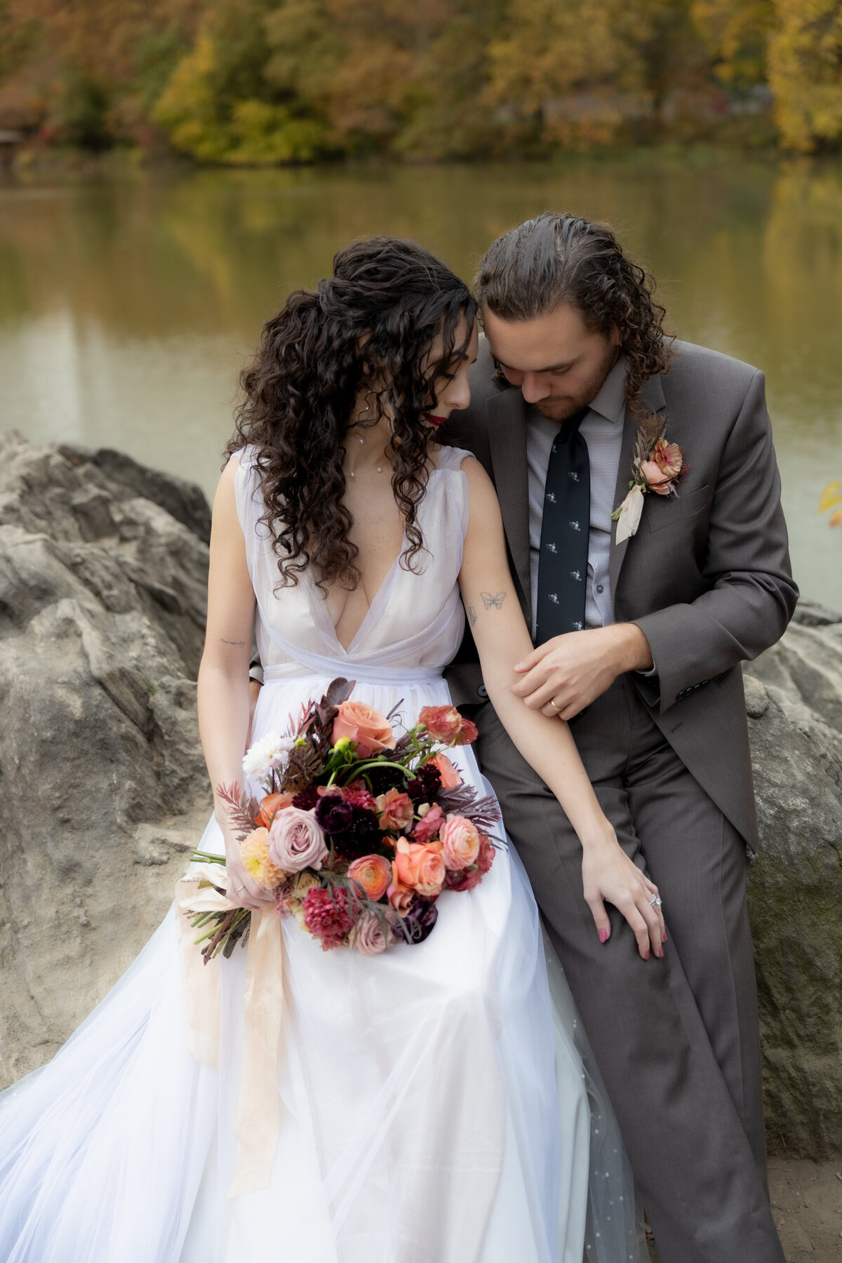 The couple standing close together surrounded by Central Park’s glowing fall foliage.