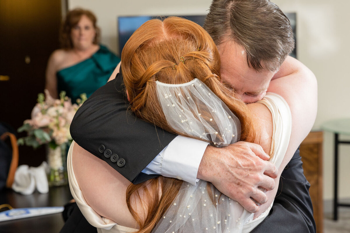 A man in a suit is hugging a woman in a white dress