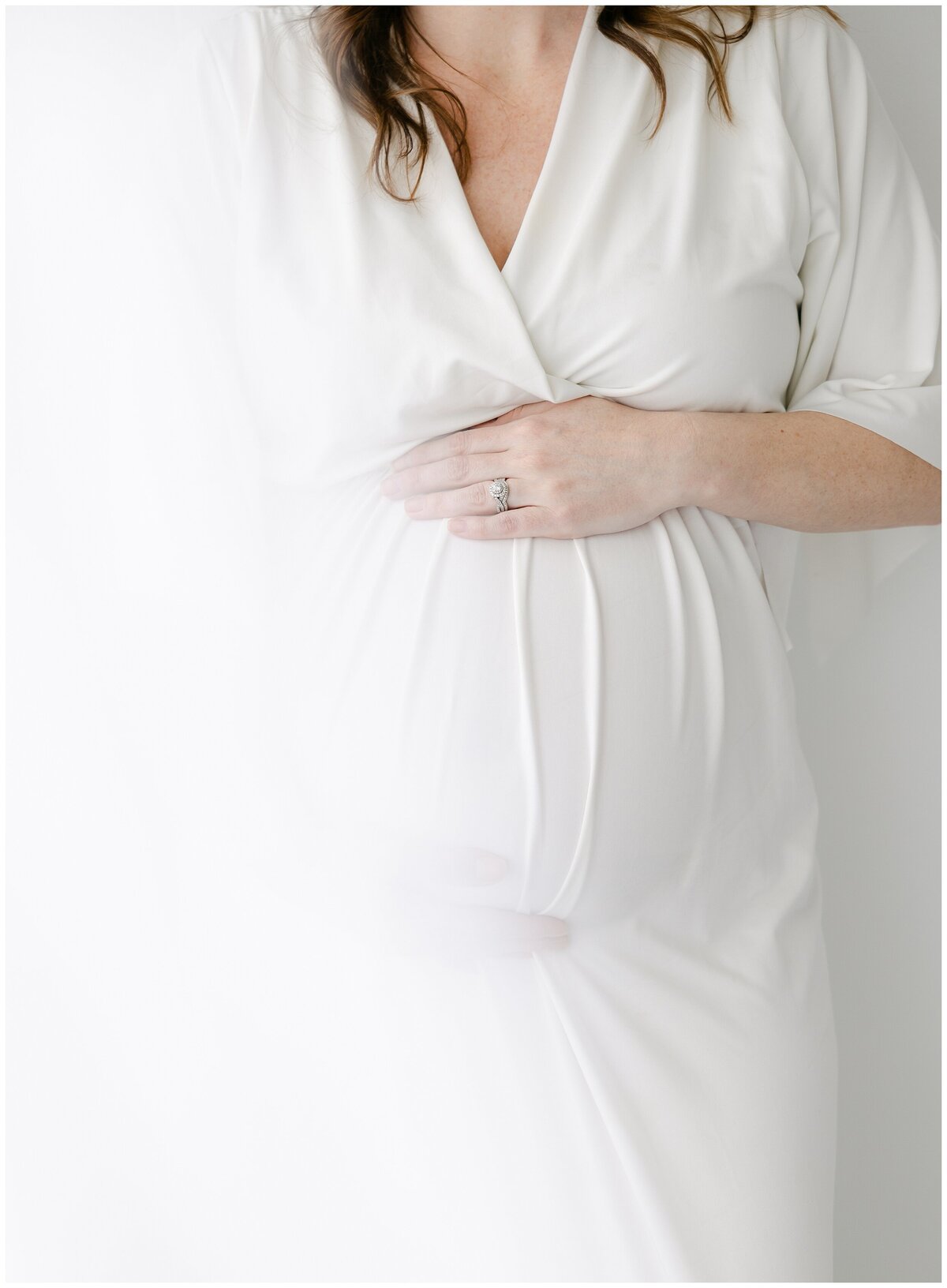 Close up of a pregnant mother in a white dress with her hand on her baby belly during her Indianapolis maternity photos.