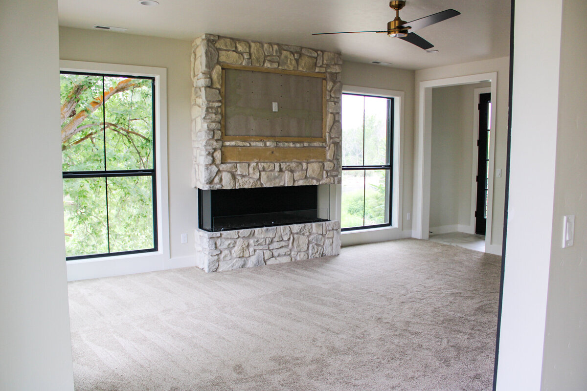 empty living space with fire place and light carpet