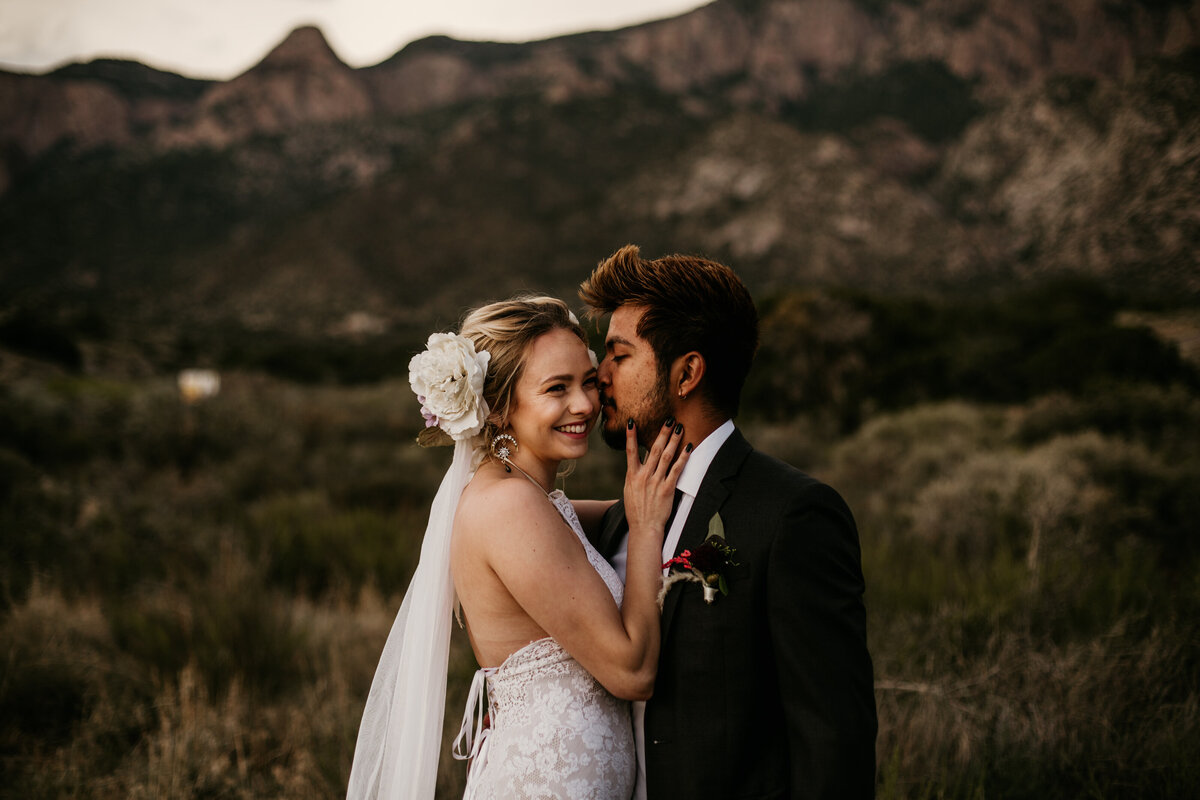 groom whispering to bride in desert