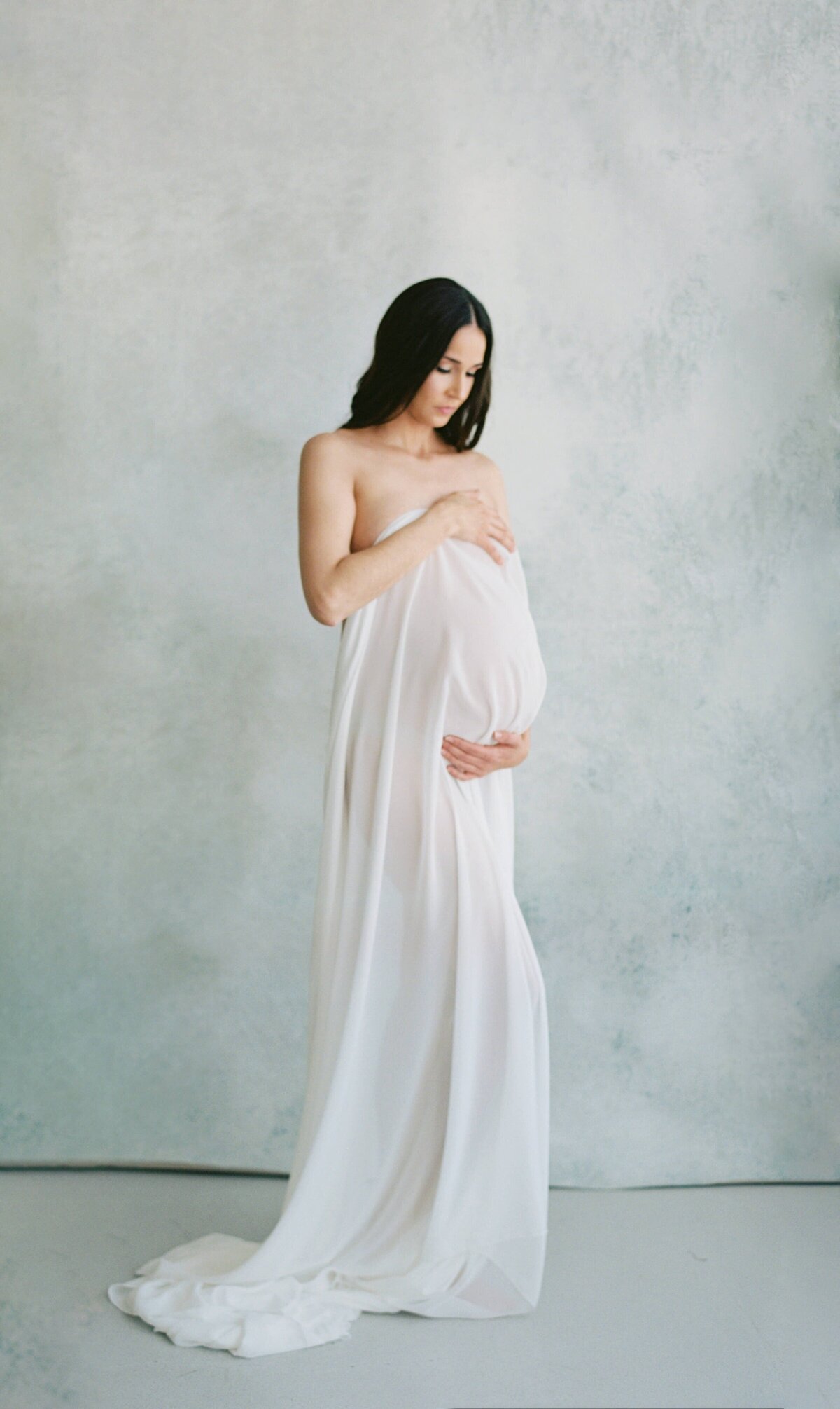 pregnant woman posing in white dress for her studio maternity photos in san francisco