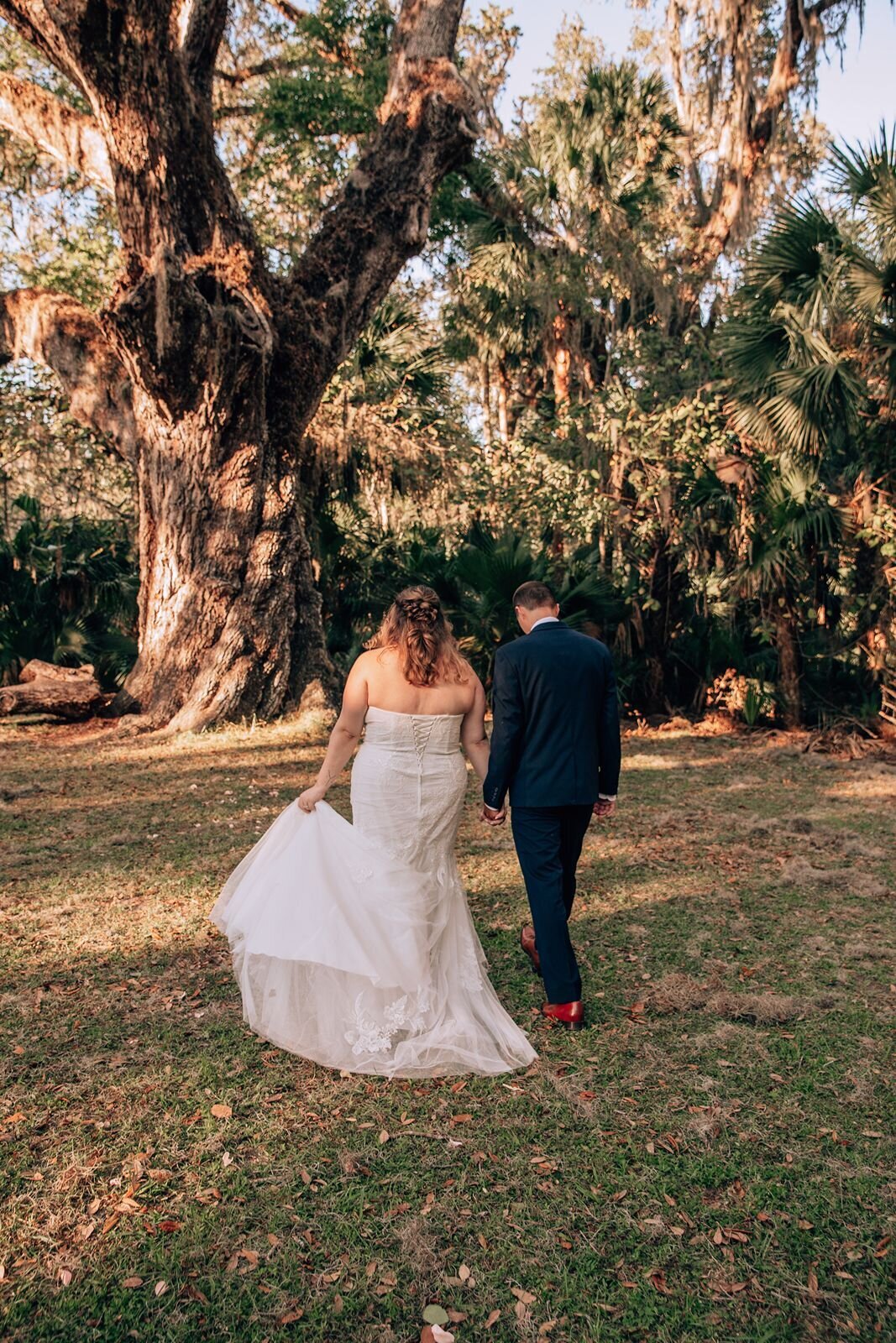 bride and groom walking together at fairchild oak in ormond beach