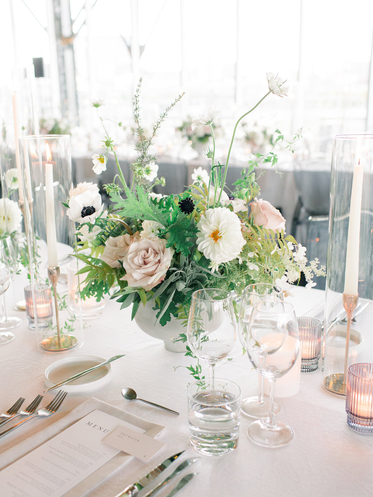 A centrepiece of lush, pastel garden flowers and greenery at a Science Centre wedding reception.