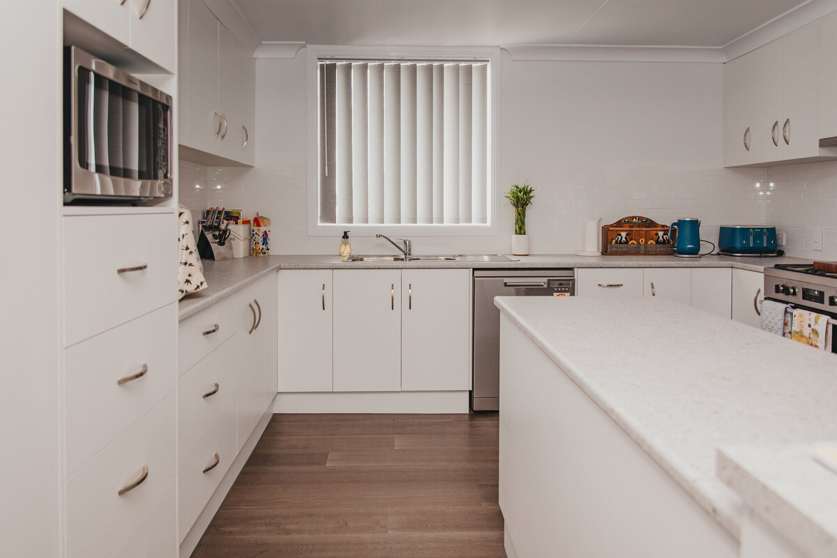 Sleek kitchen design with white Venetian blinds, providing light filtering and privacy.