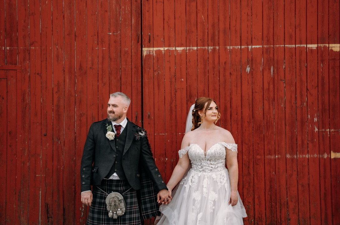 Bride and groom infront of red shutter on wedding day at enterkine house hotel