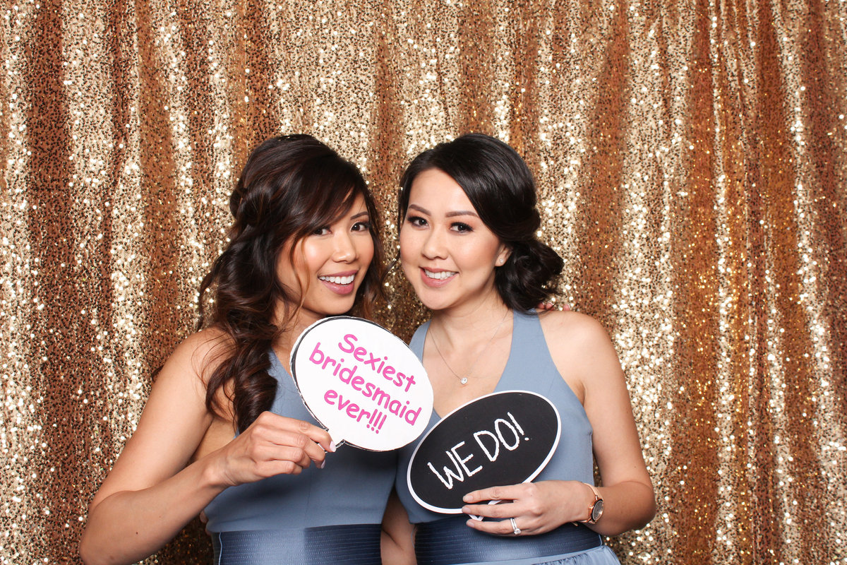 Two bridesmaids pose together in a photo booth rental from Three16 Photography