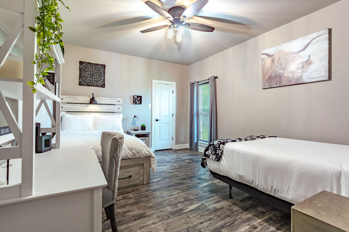 Bedroom with two beds with comfortable bedding in this five-bedroom, 3-bathroom vacation rental house for up to 10 guests with free wifi, private parking, outdoor games and seating, and bbq grill on 2 acres of land near Waco, TX.