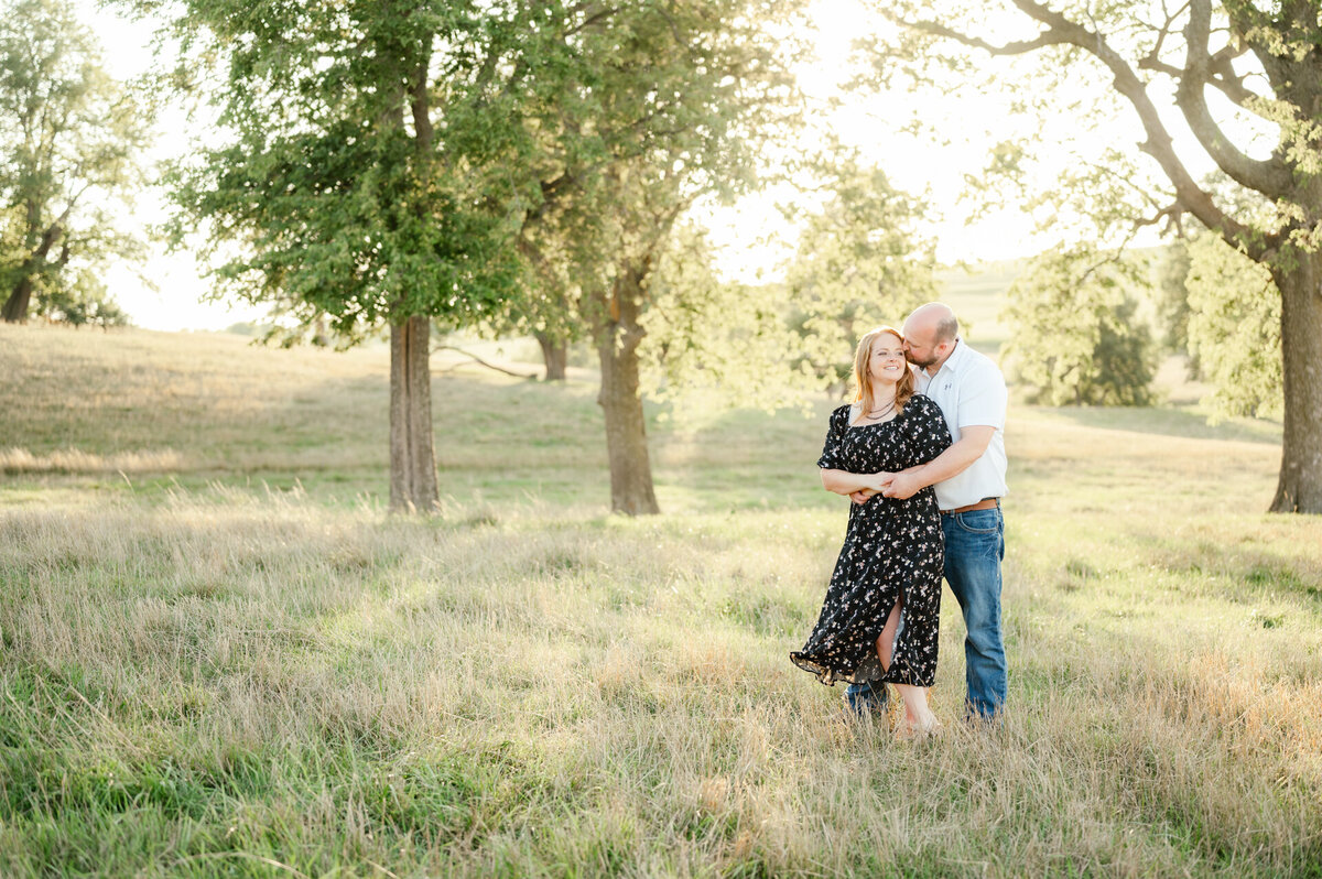 man and woman hug in a sun lit open field