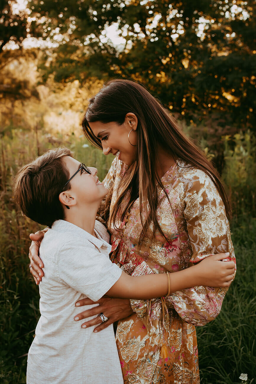 a mother and son embraced looking at each other at sunset in a beautiful field