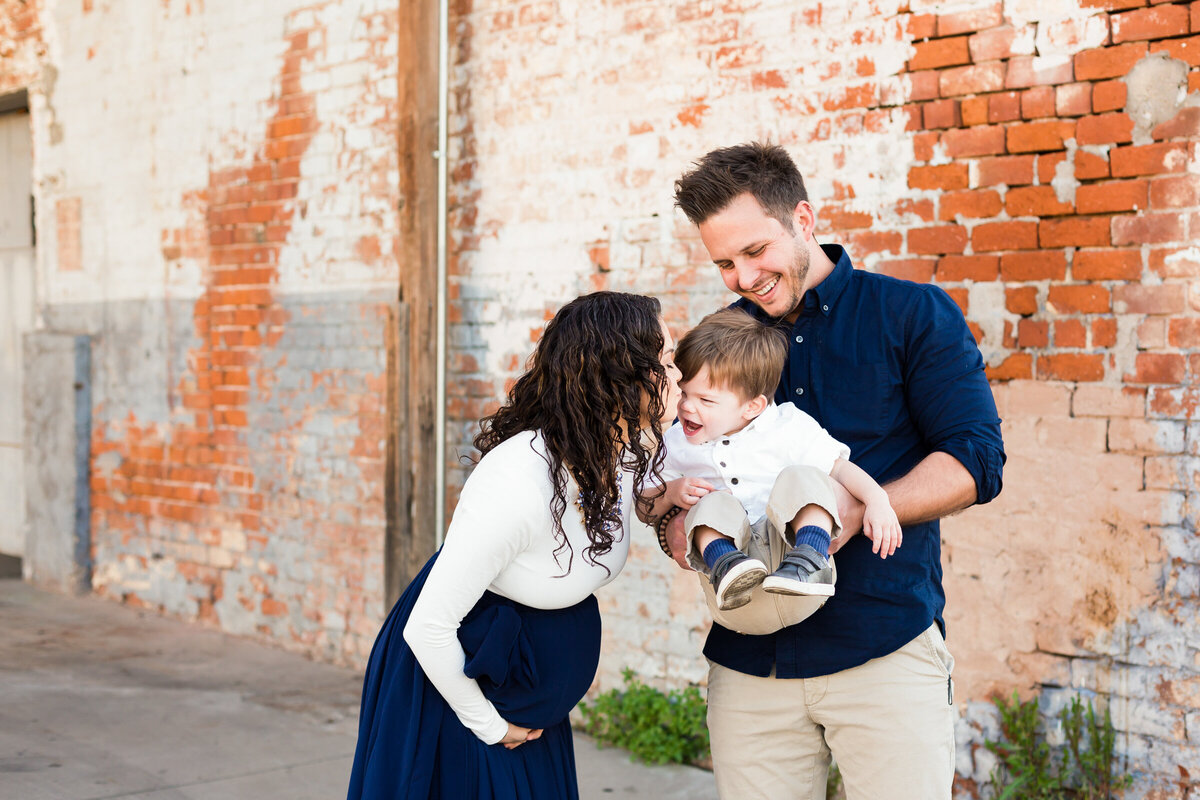 family playing together while mom holds baby bump