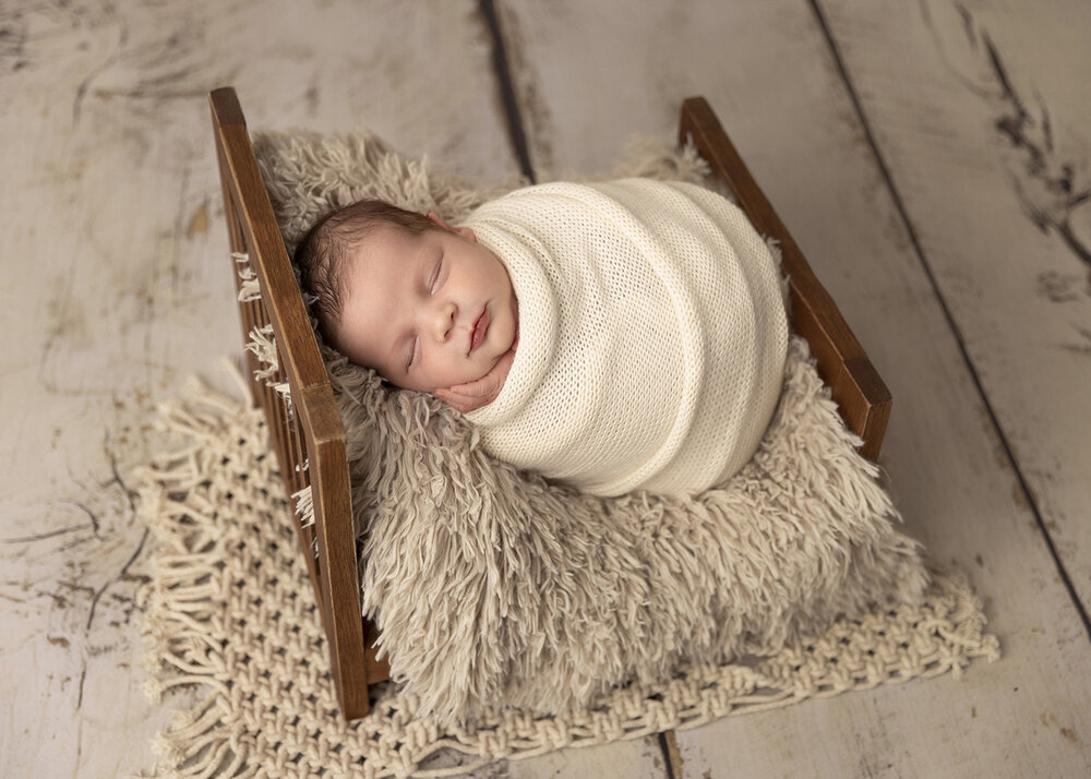 NEWBORN_BABYBOYINWOODENBEDWRAPPEDINCREAM