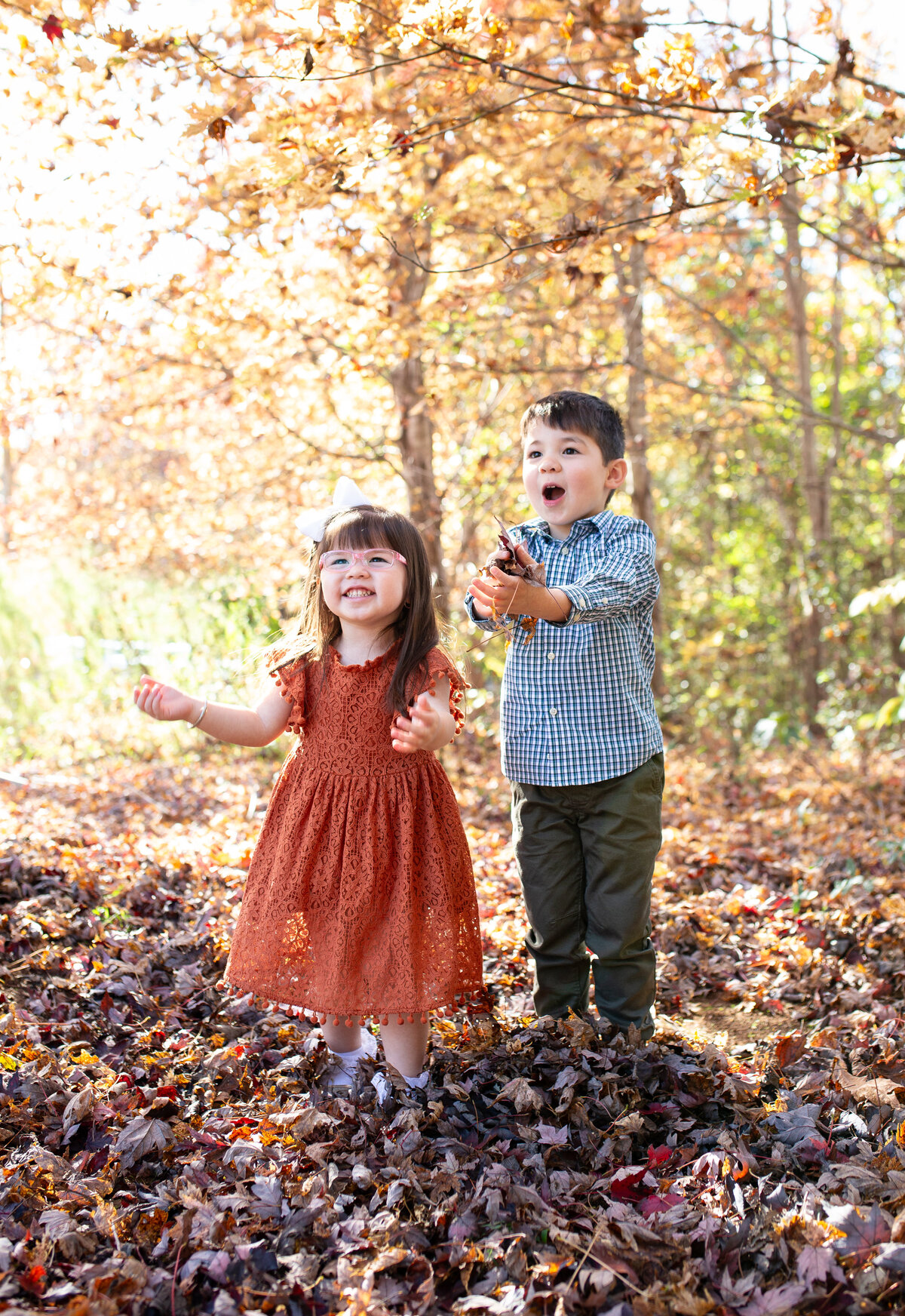 children playing with leaves during mini photo session in wake forest