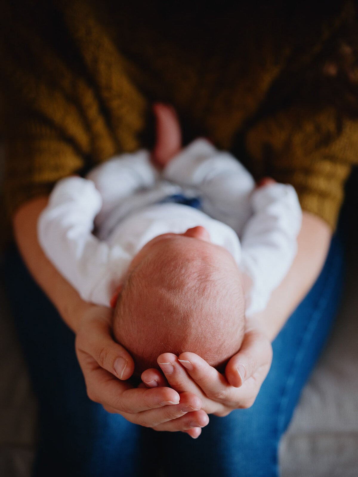 Cose-up of mom's hands cradling her newborn baby's head during an at home santa monica newborn photography session.