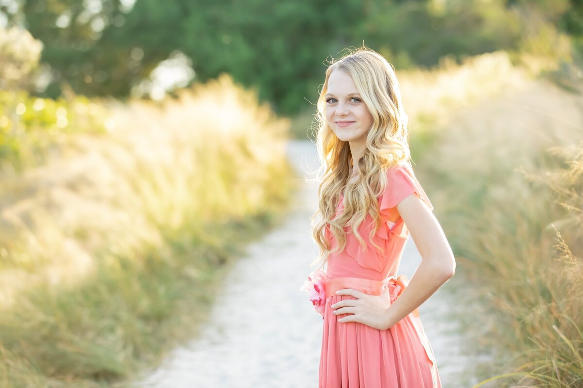 a close up portrait of a 12 year old girl in a coral dress on the beach path heading out to Siesta Key Beach