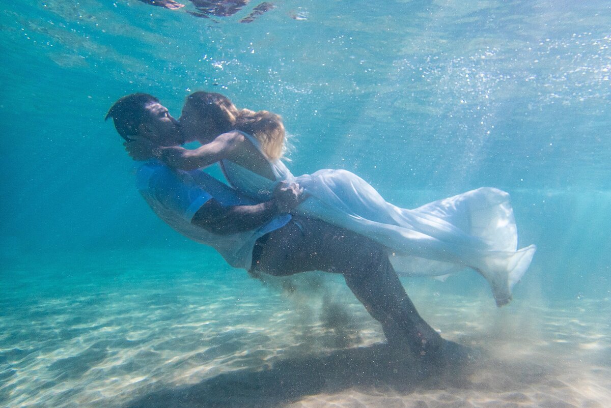 A bride and groom kiss underwater in their wedding dress in Hawaii