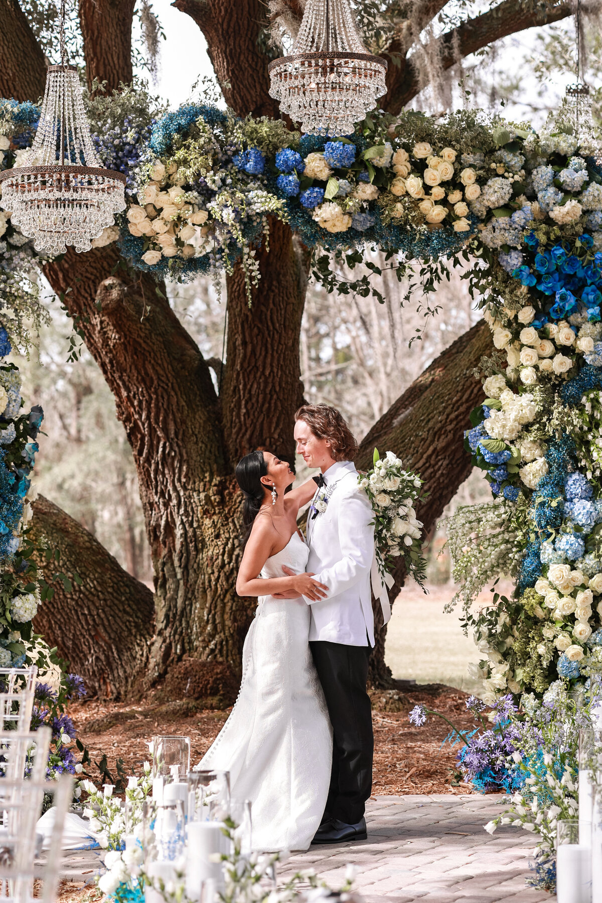 bride and groom looking at each other after wedding ceremony with blue and white florals and chandeliers at Hewitt Oaks in Bluffton South Carolina by South Carolina wedding photographer by  Amanda Richardson Photography