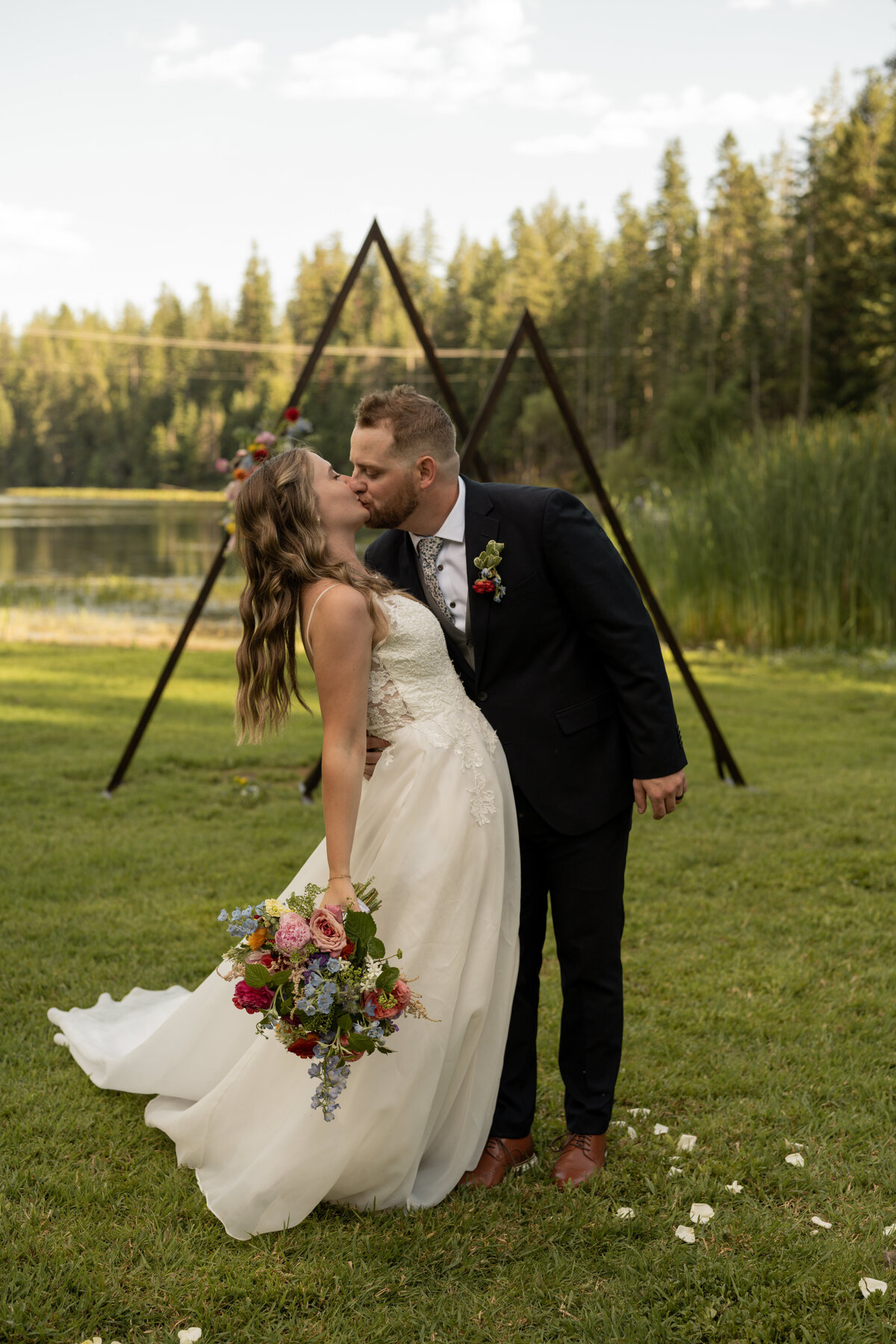Bride and groom kissing in front of Idaho lake taken by wedding photographers in Idaho