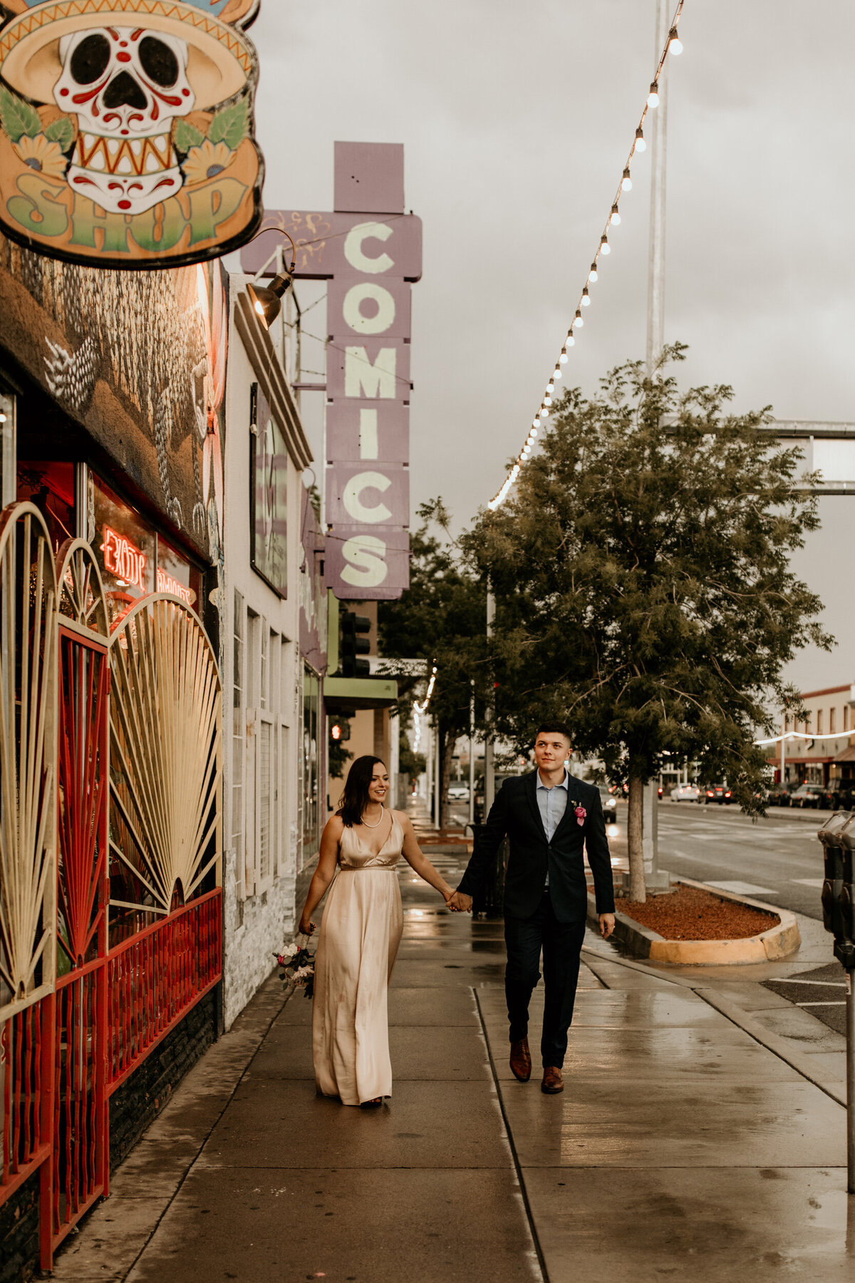 newlyweds walking down Central Ave in the rain in downtown Albuquerque