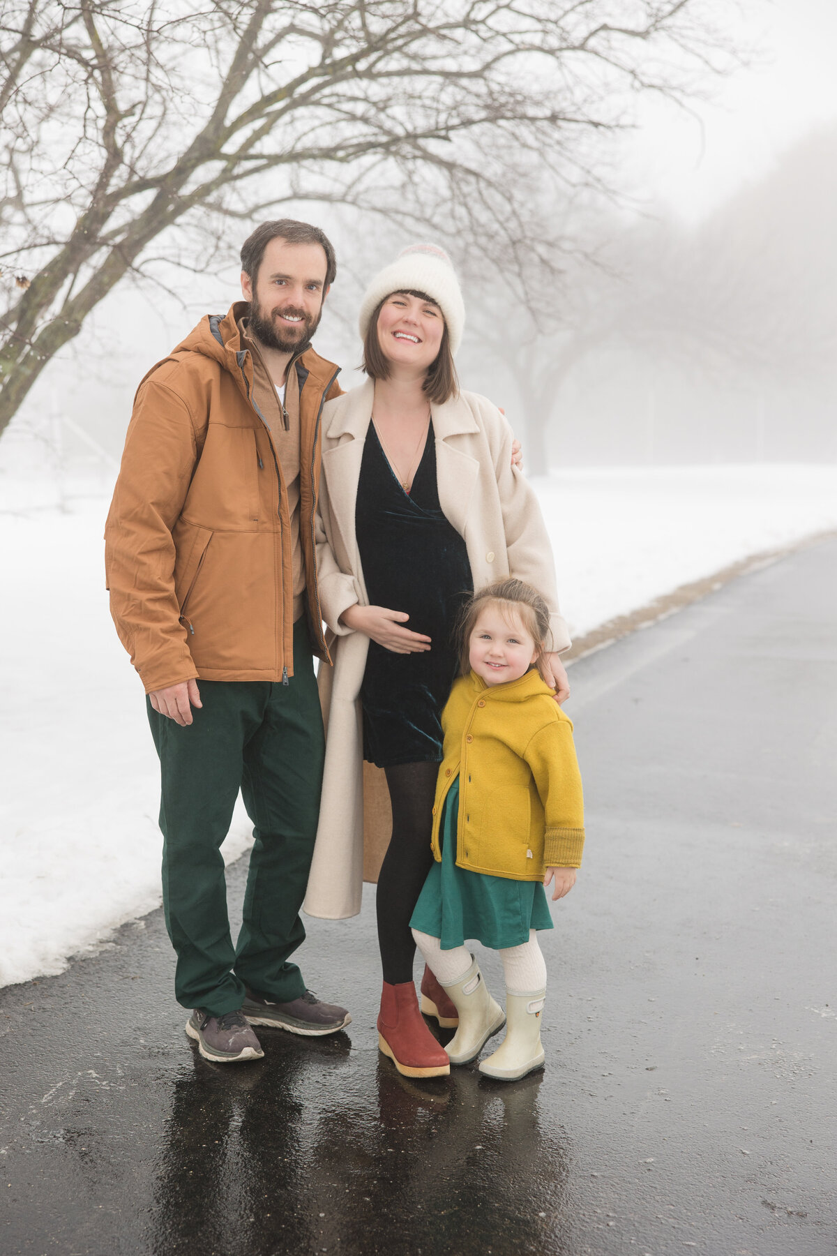Parents and their young daughter standing together and smiling